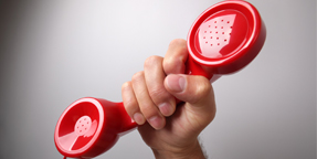 Close up photograph of a hand holding up a red telephone